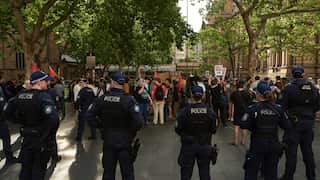 A group of police officers standing facing a group of protesters 