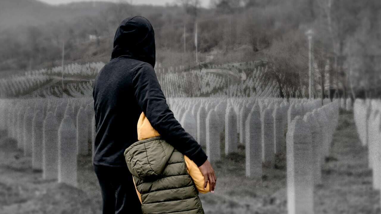 An adult figure wears a hoodie and hugs a child wearing a hoodie. We can only see their backs. There is a background image of graves