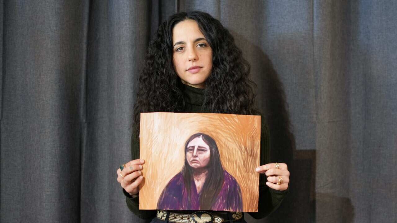 A woman with dark curly hair holding a courtroom sketch
