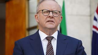 A man in a blue suit with white hair wearing glasses 